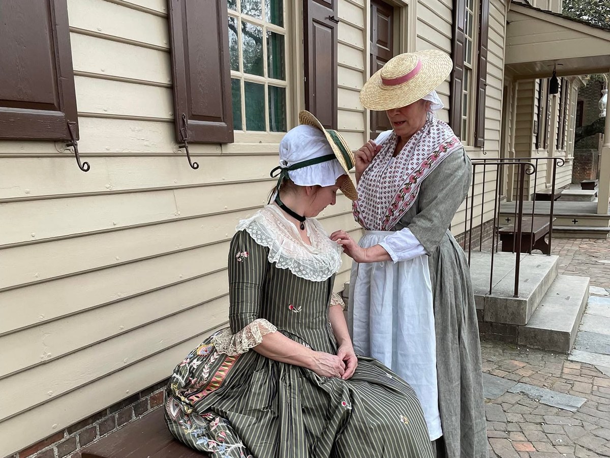 Two women in 1770s dress, one seated in an embroidered gown